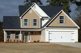 Two-story house with a white garage door, brown brick and siding, and blue shutters.