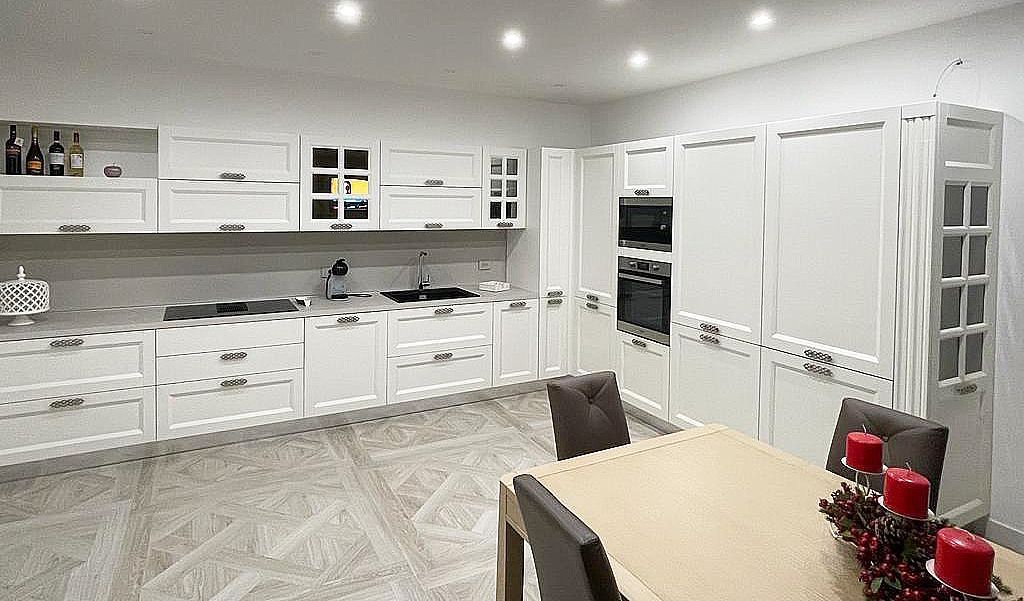 Cucina bianca con mobili, fornelli, forno e tavolo da pranzo.