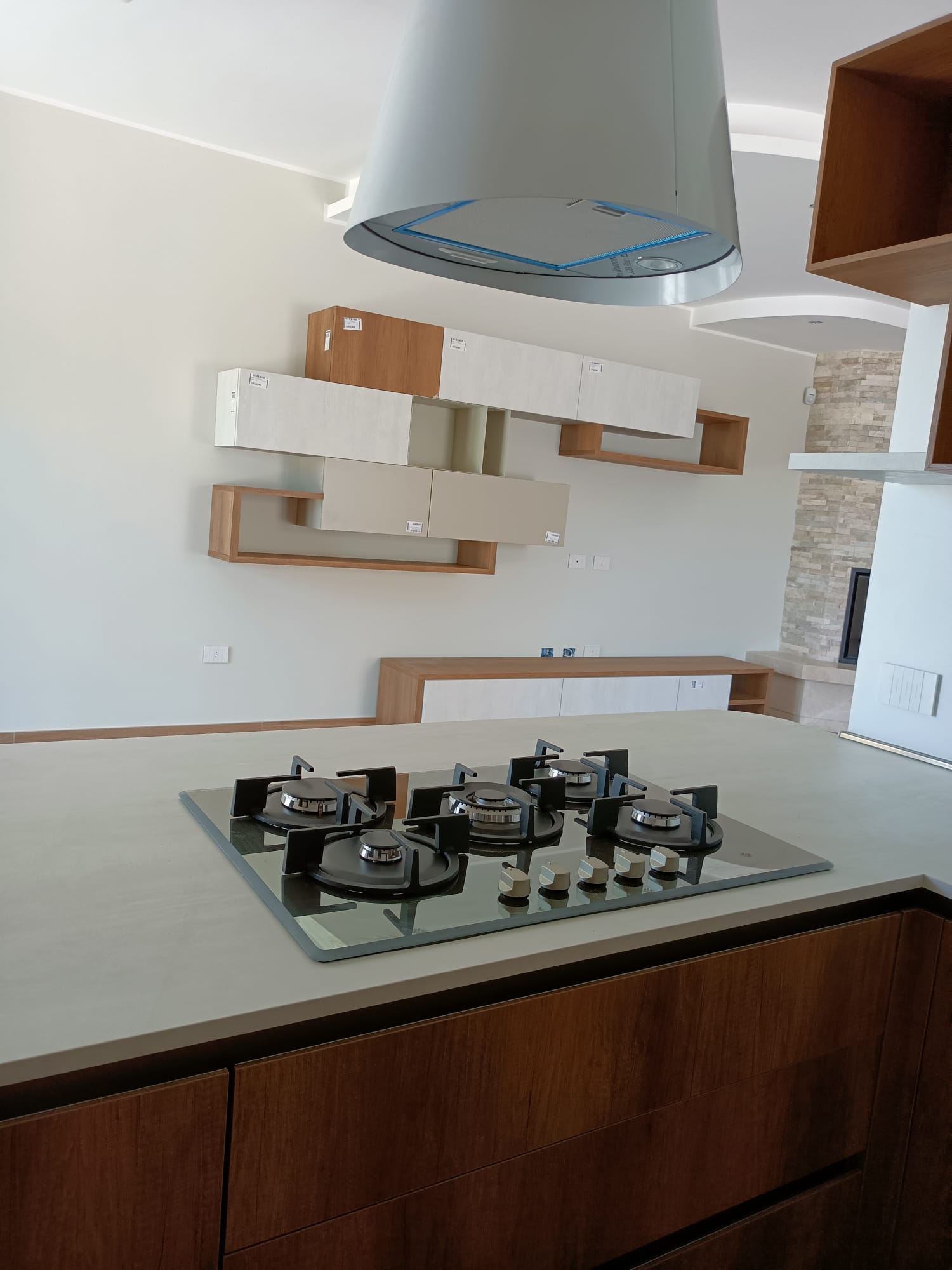 Cucina moderna con piano cottura, mobili e cappa aspirante.