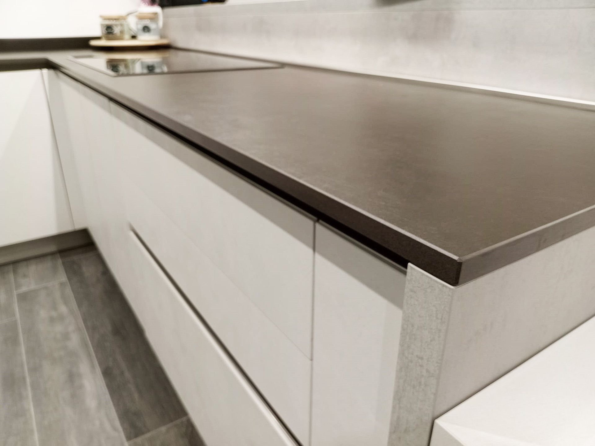 Cucina moderna con piano di lavoro scuro e mobili chiari.