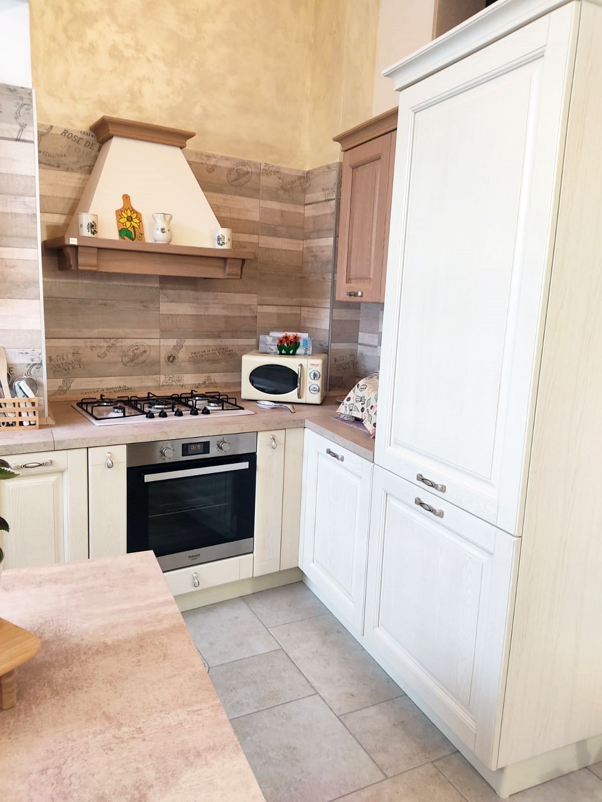 Cucina con mobili beige, forno, cappa aspirante e microonde.