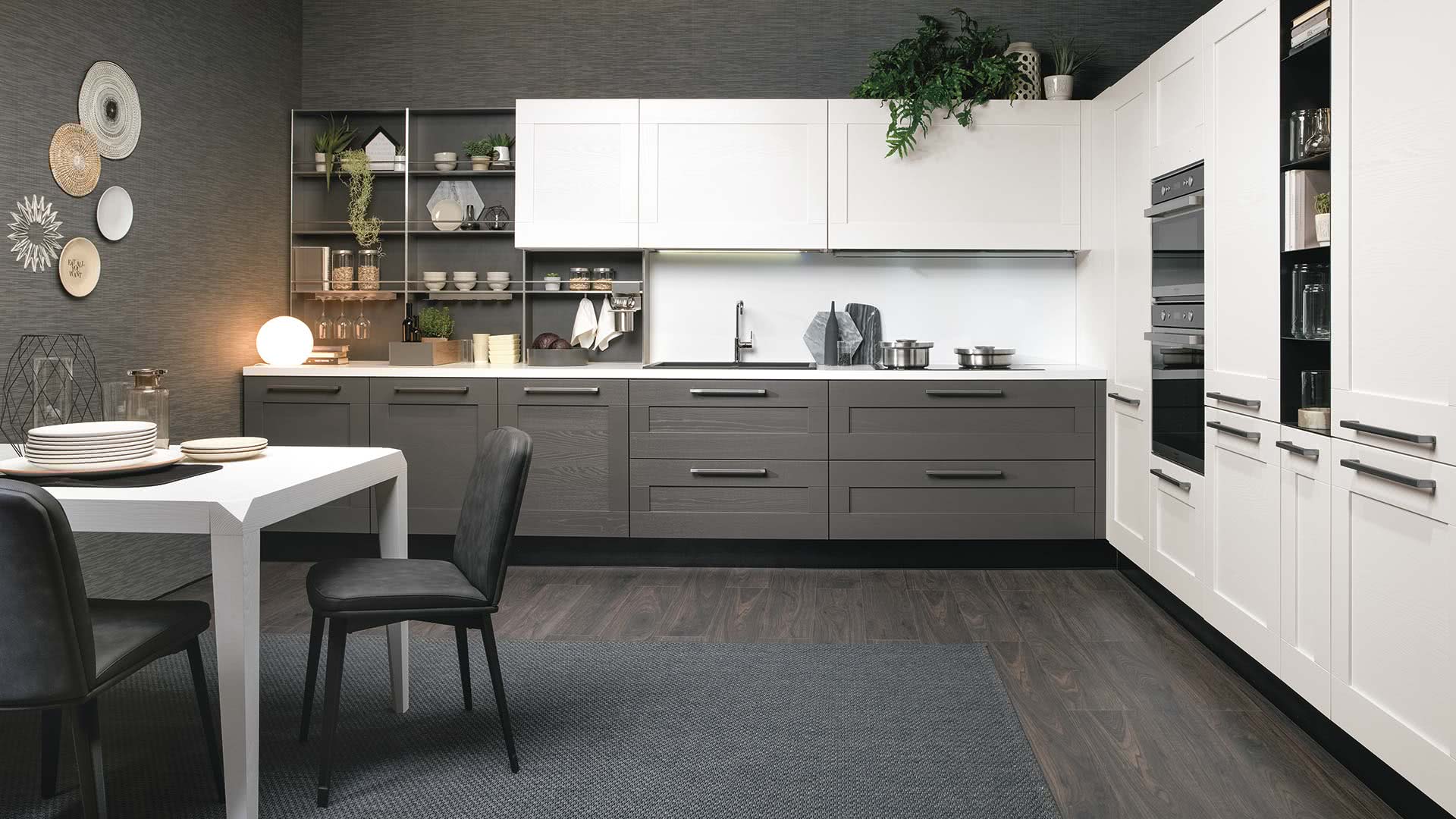 Cucina moderna grigia e bianca con zona pranzo; pavimenti in legno scuro, mensole e tappeto grigio.