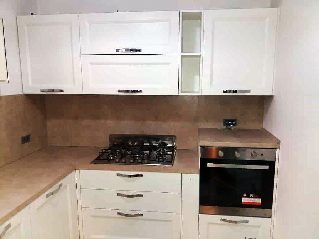 Mobili da cucina e ripiani bianchi con forno e piano cottura a gas integrati.
