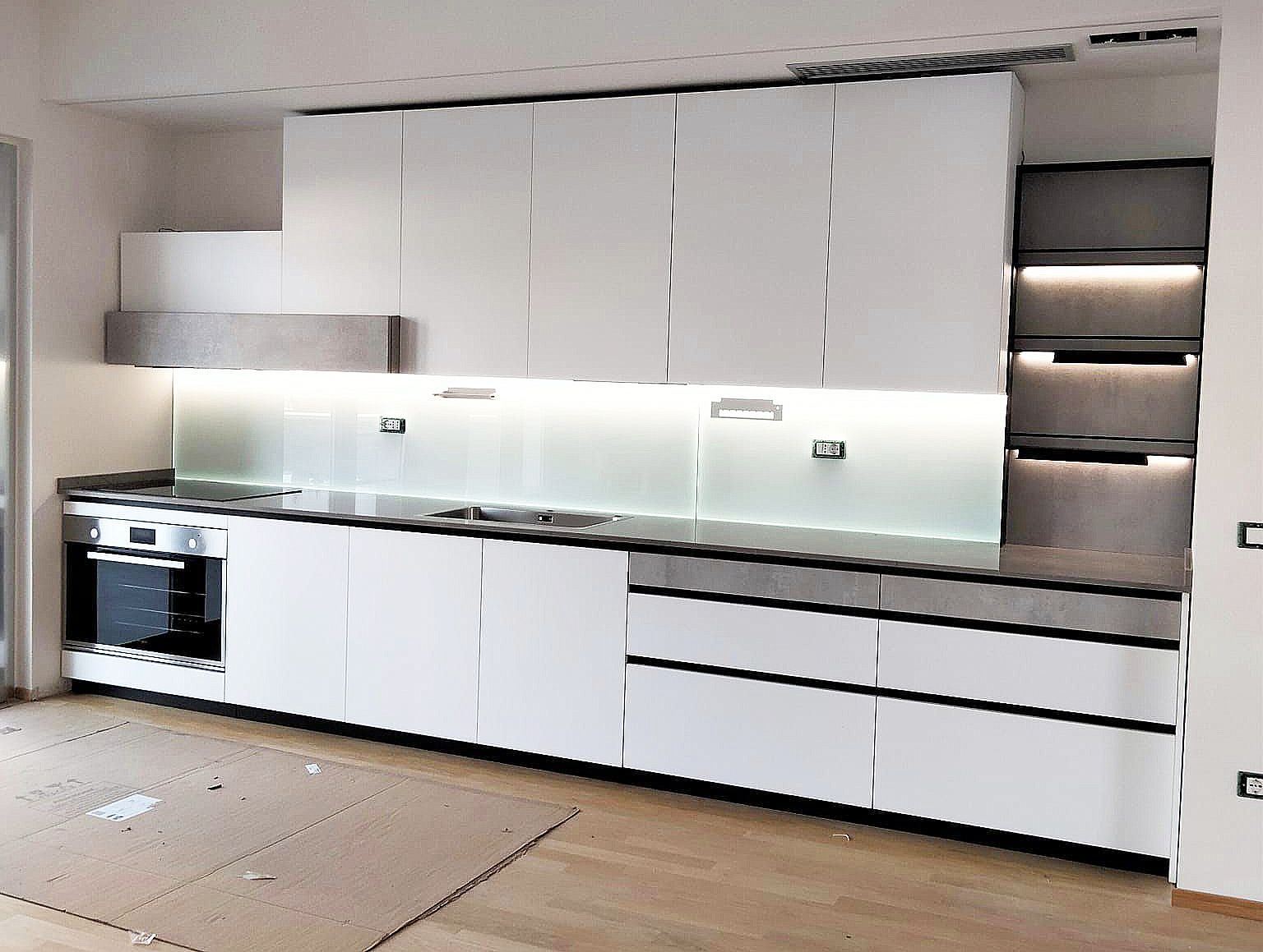 Moderni mobili da cucina bianchi con ripiani ed elettrodomestici.