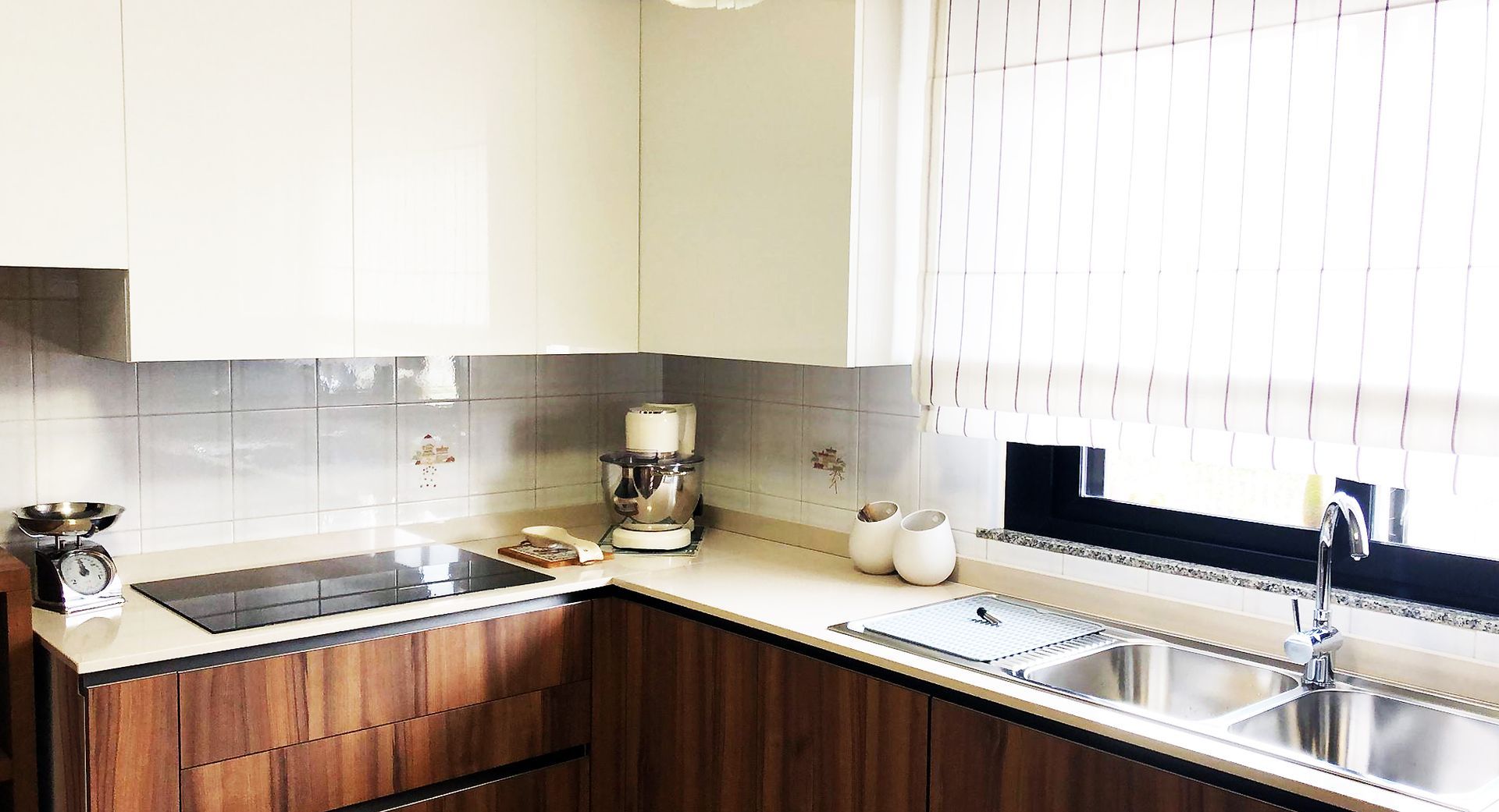 Cucina moderna con mobili in legno, lavello in acciaio inox e ripiani beige.