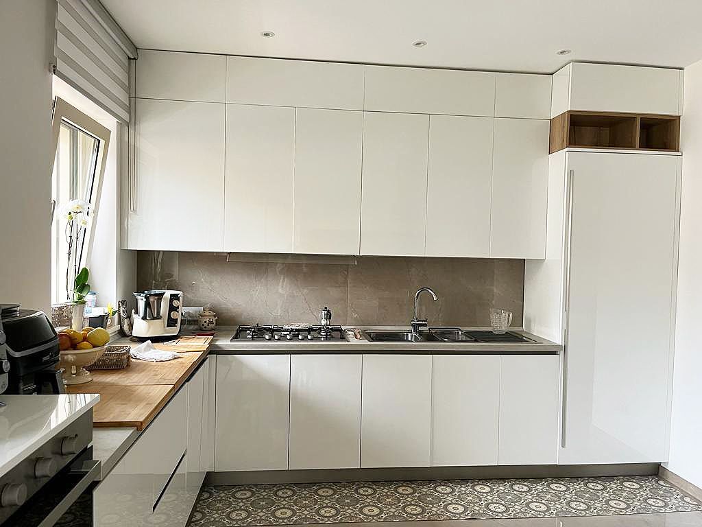 Cucina moderna bianca con mobili, lavello e piano cottura.