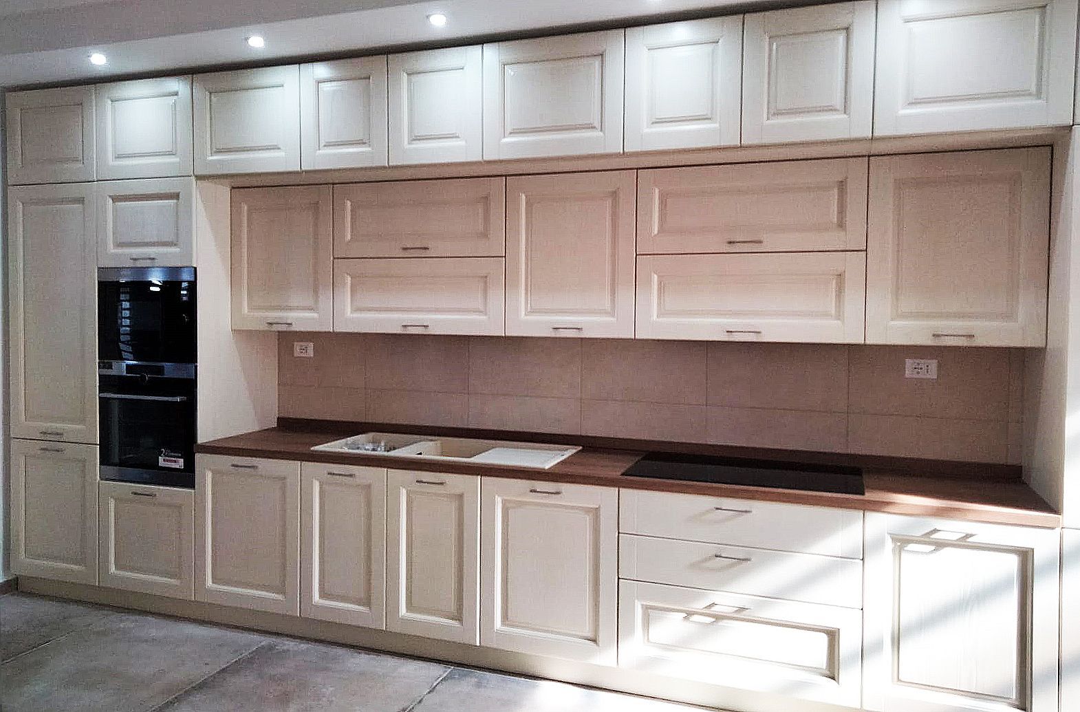 Mobili da cucina color crema con forno incorporato, piano di lavoro e pensili.