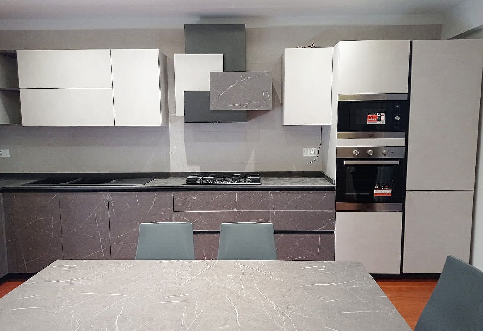Cucina moderna con mobili, elettrodomestici e isola grigi e bianchi.