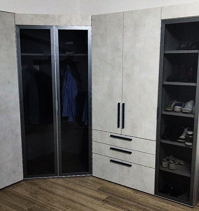 Armadio angolare con mobili grigi, scomparti aperti per i vestiti e ripiani per le scarpe.