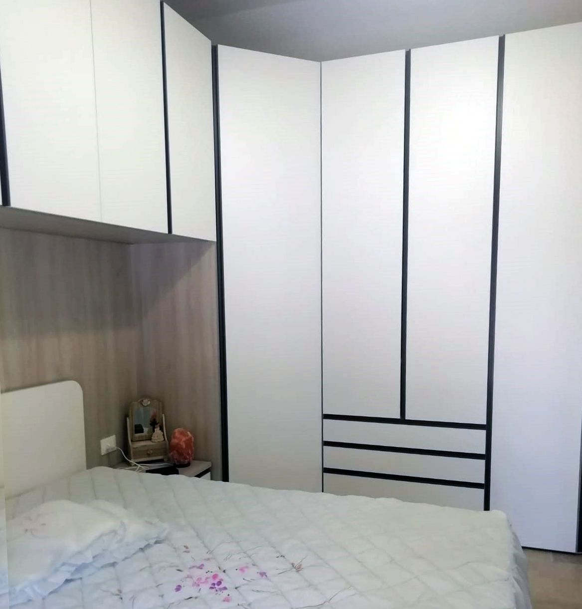 Armadio bianco con finiture nere; letto con lenzuola bianche; comodino.