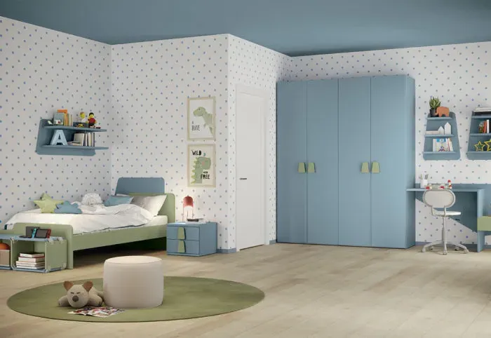 Cameretta per bambini blu e verde con letto, armadio, scrivania e tappeto rotondo.