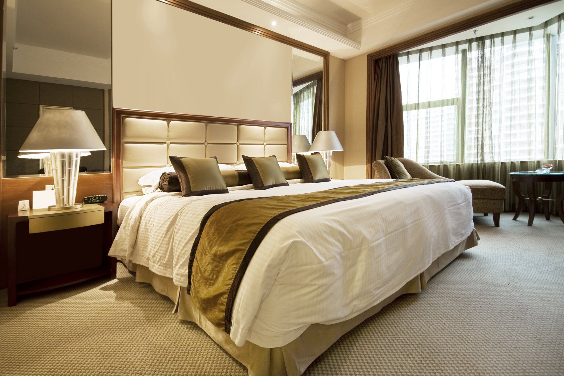 Camera d'albergo con letto king-size, lampade, finestra e colori neutri.