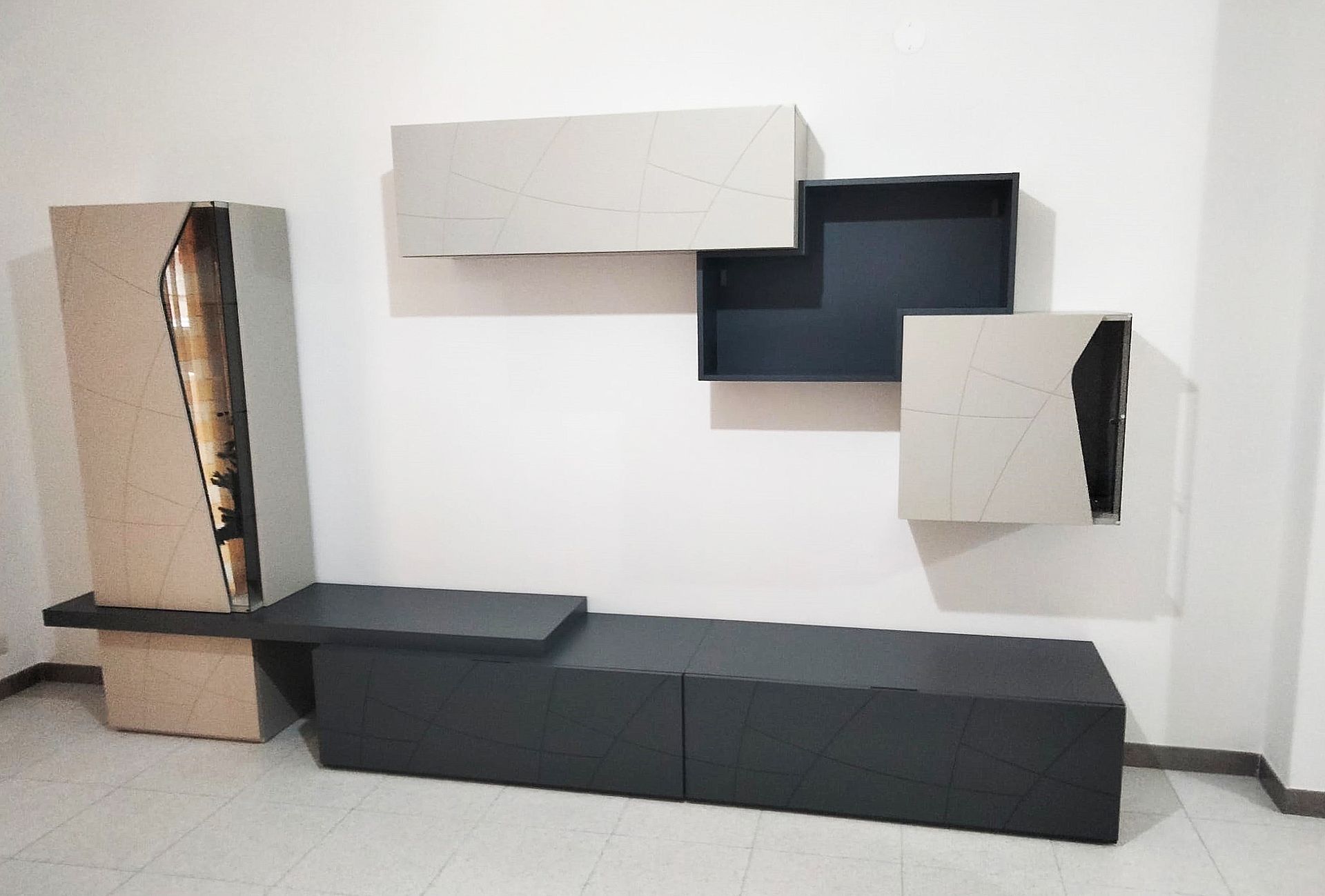 Moderna parete attrezzata con mobili grigio chiaro e scuro e ripiani sospesi.
