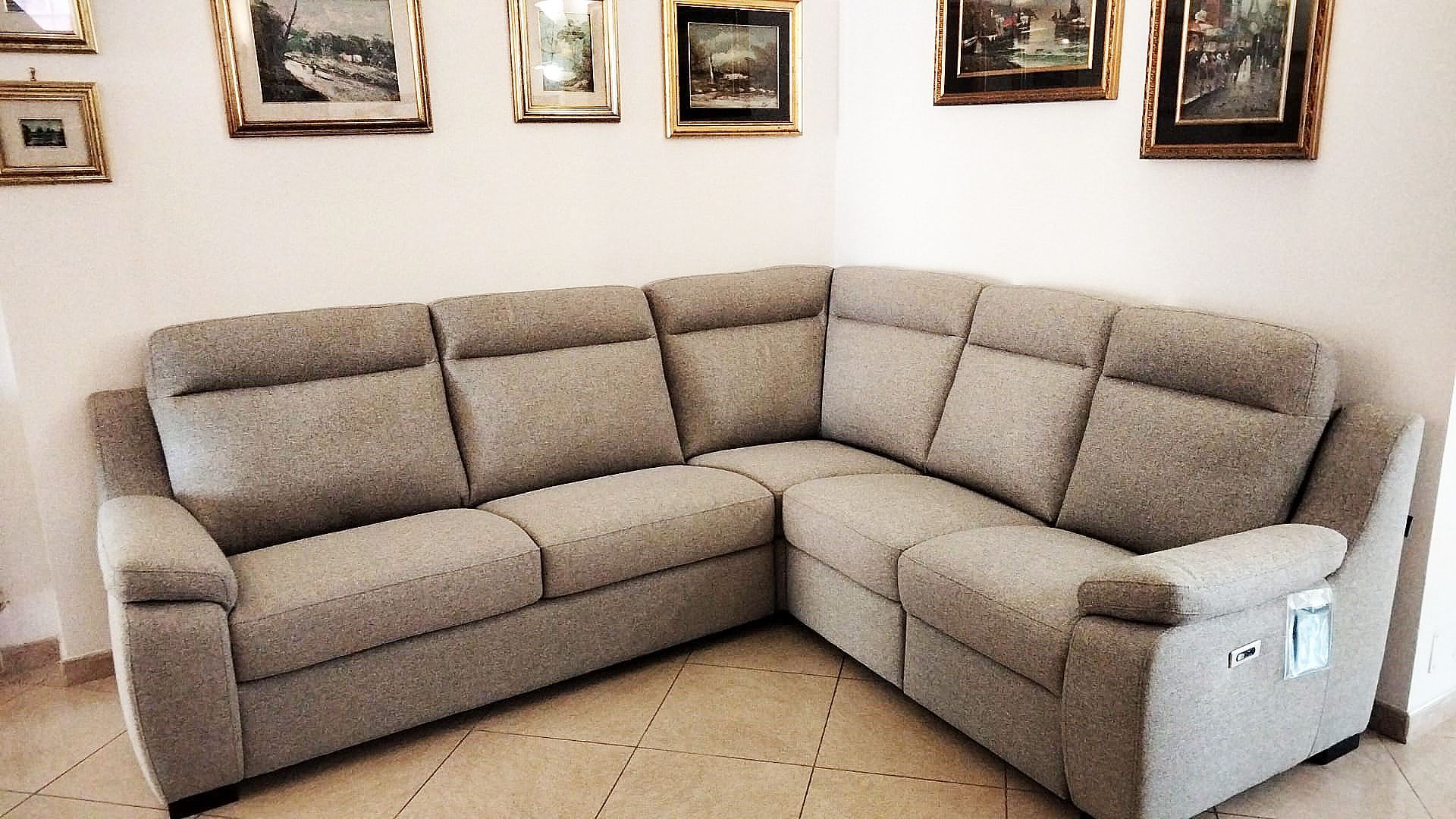 Un divano componibile grigio chiaro in una stanza con quadri incorniciati su pareti bianche.