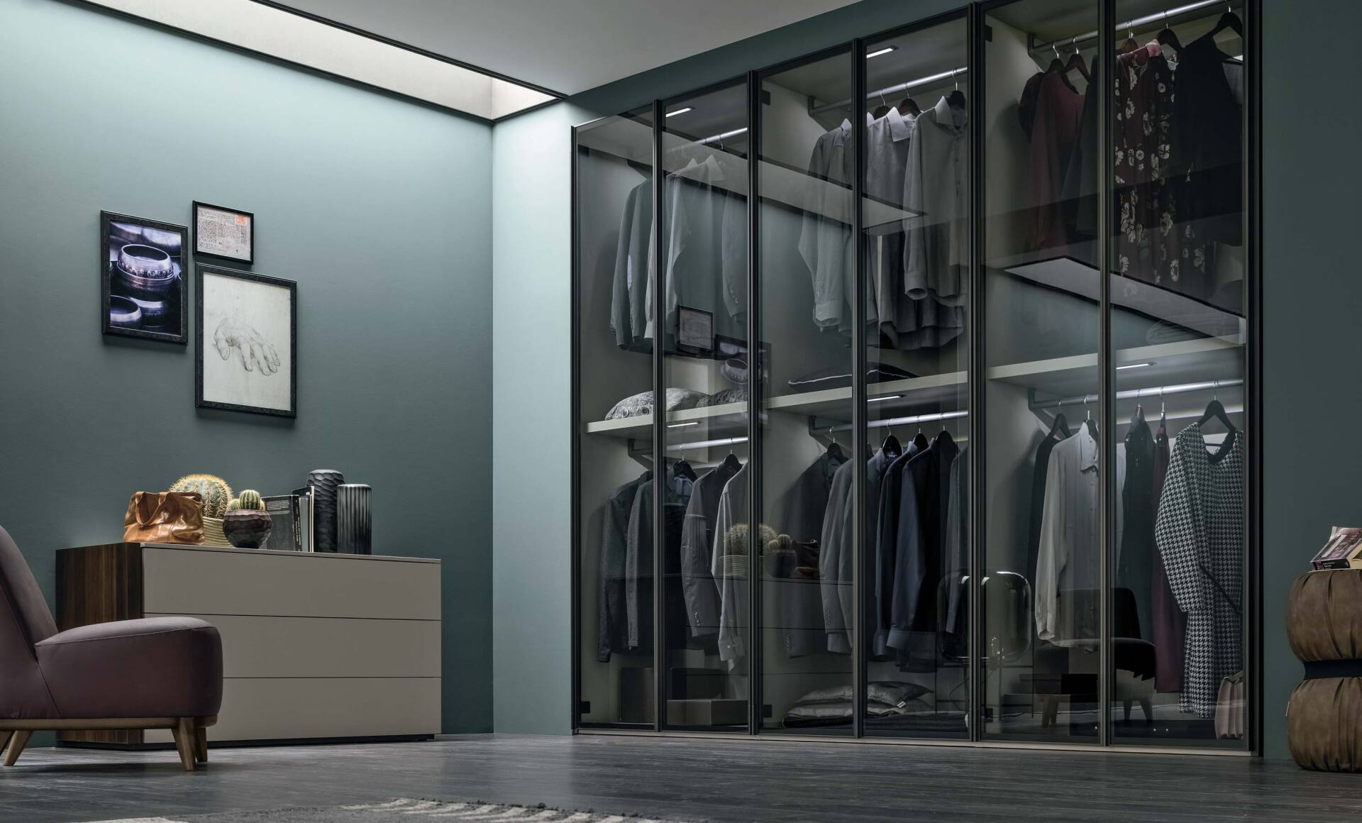 Una moderna cabina armadio con porte in vetro, abiti esposti e pareti dai colori neutri.