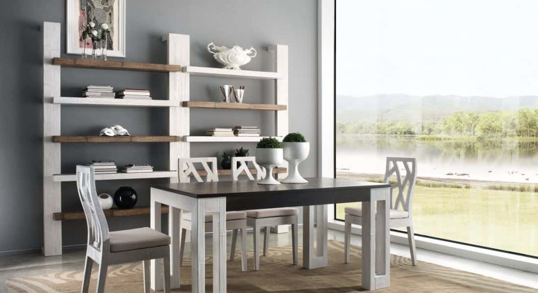 Sala da pranzo con tavolo, sedie e librerie. Mobili bianchi e marroni. Ampia finestra con vista sul lago.