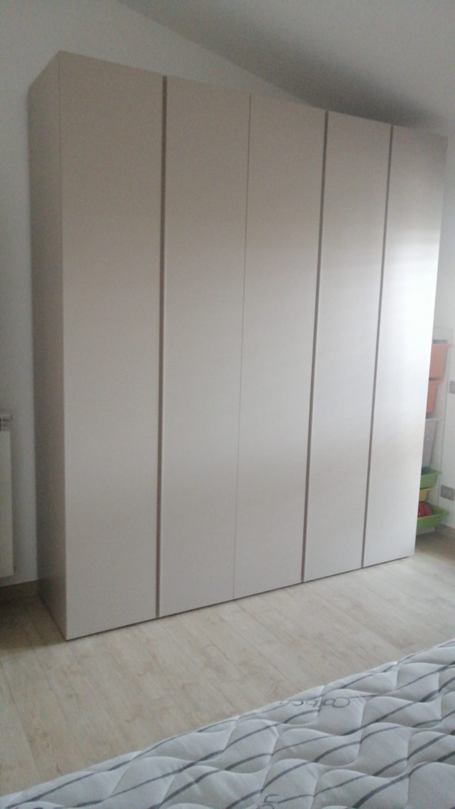 Grande armadio beige a sei ante in una camera da letto.
