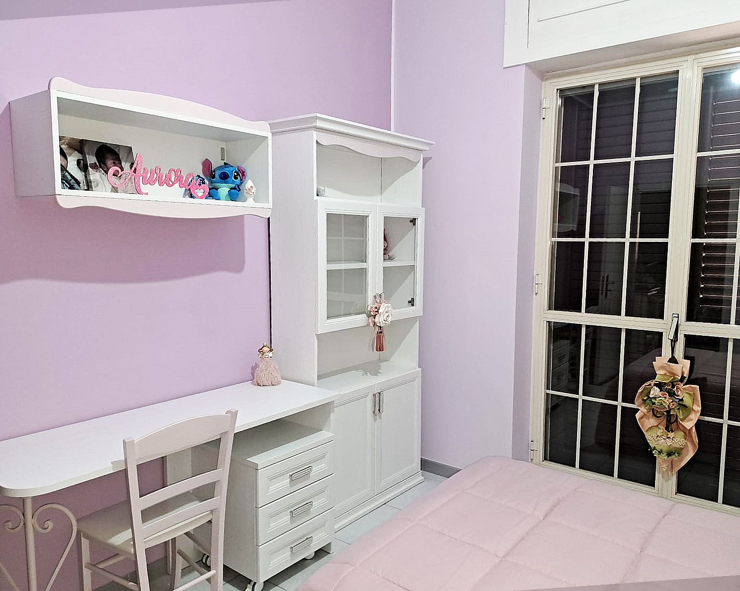 Camera da letto con mobili bianchi, pareti rosa e una finestra.