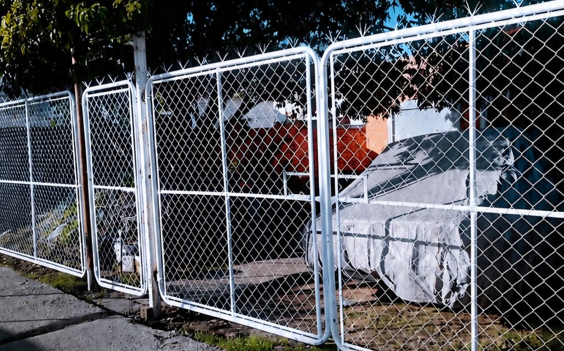 Una valla de malla metálica rodea tiendas de campaña y lonas en una zona de acampada al aire libre.