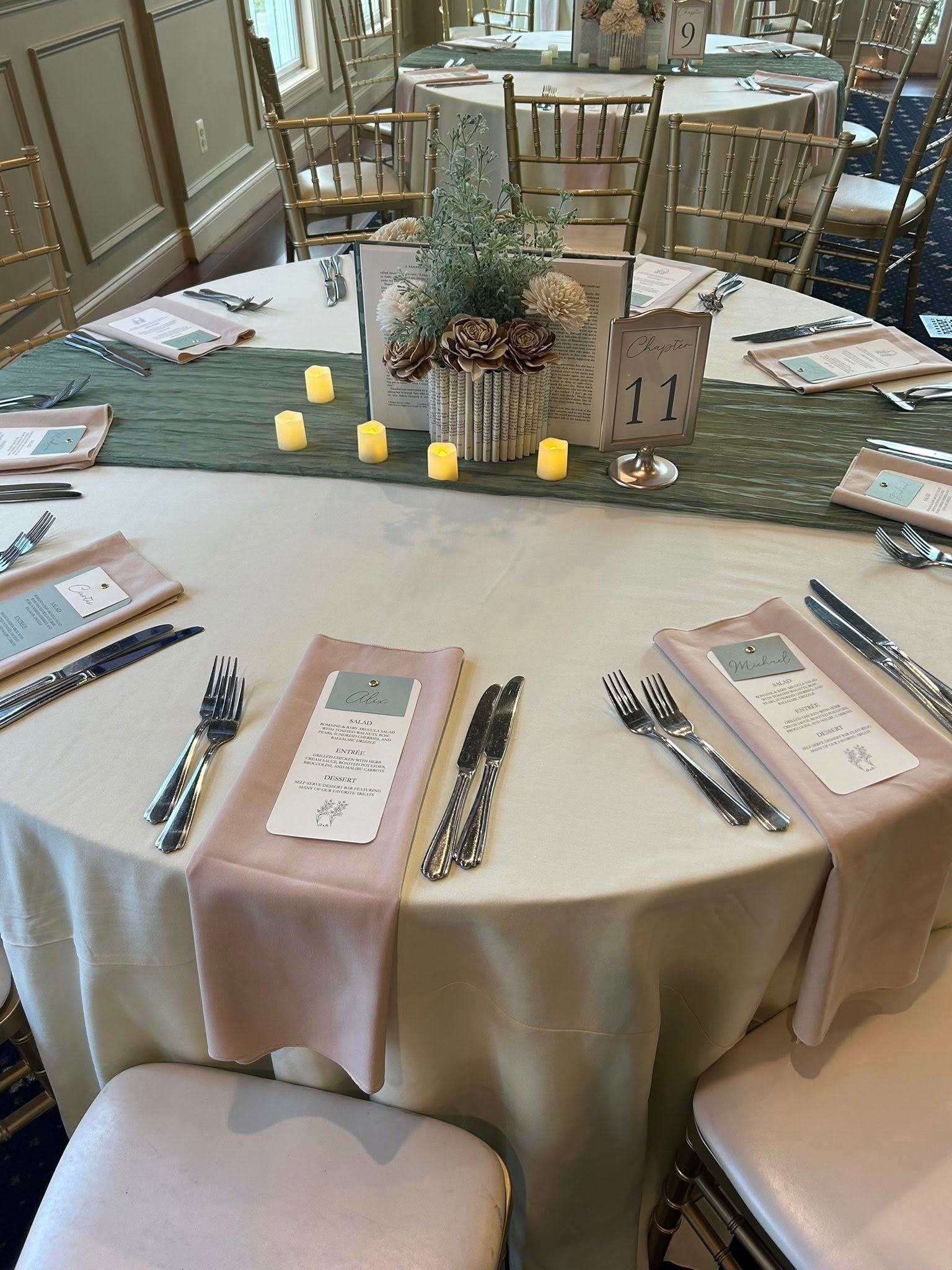 Round table set for a formal event with centerpieces, place settings, and candles.