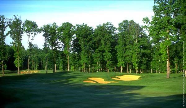 Golf course fairway with two sand traps surrounded by trees.