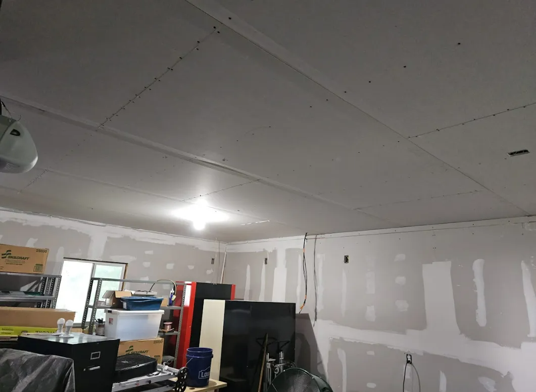 Garage interior with unfinished drywall on walls and ceiling.