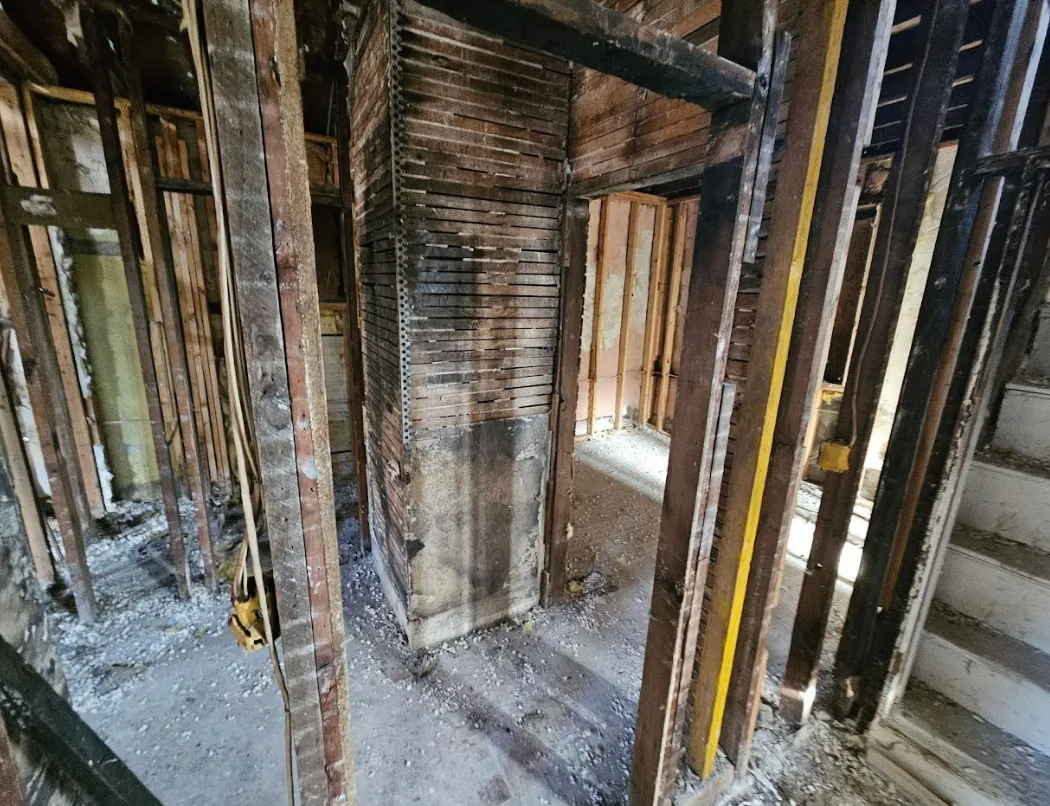 Interior view of a house under construction. Exposed wooden framing, a doorway, and a window.