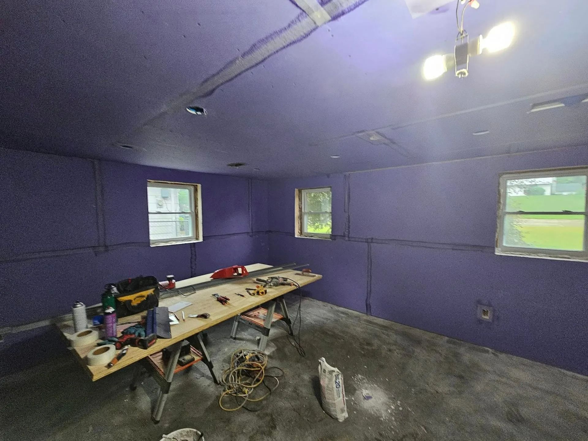 Purple-painted workshop interior with windows, workbench, and tools.