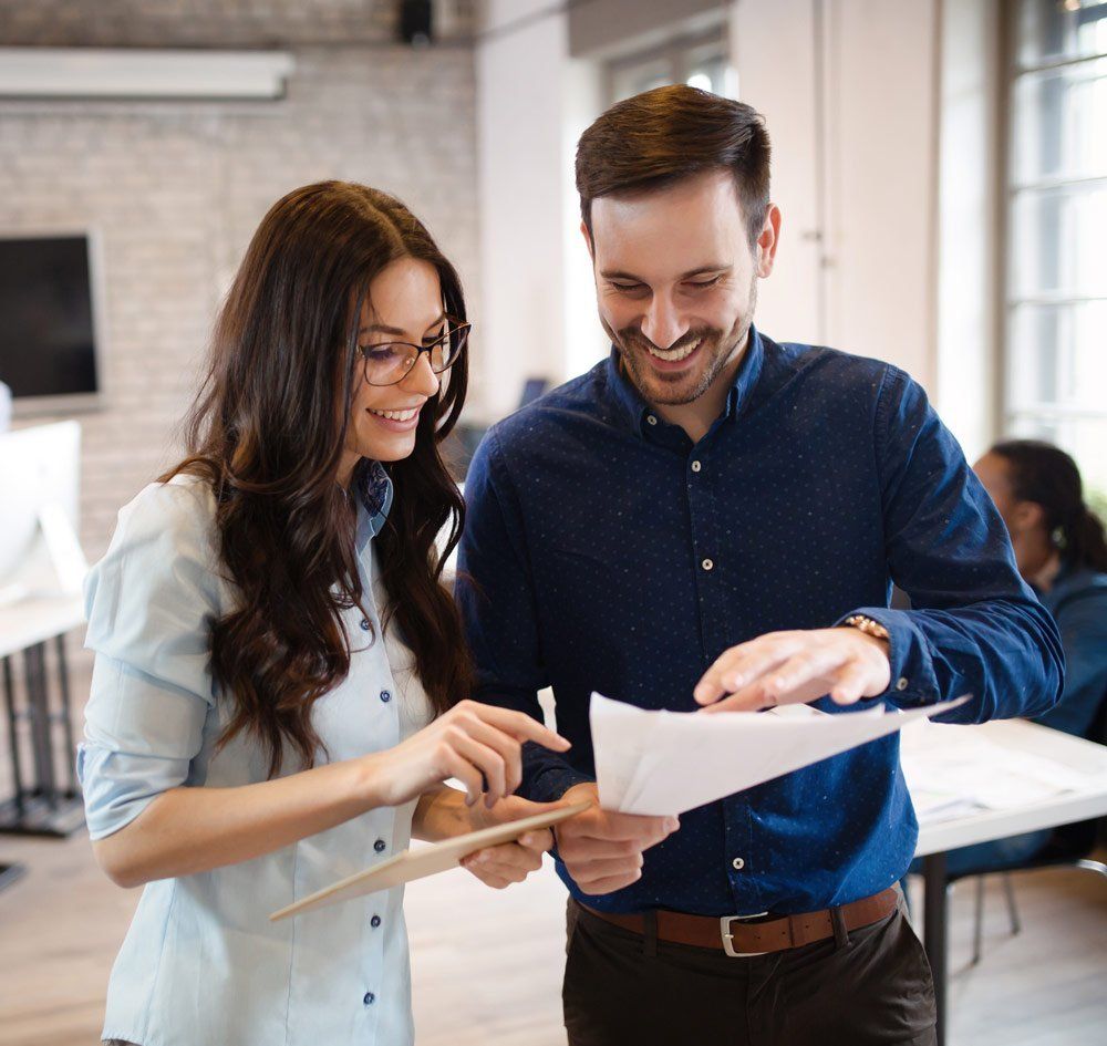 Woman and man looking at papers together, smiling in an office.