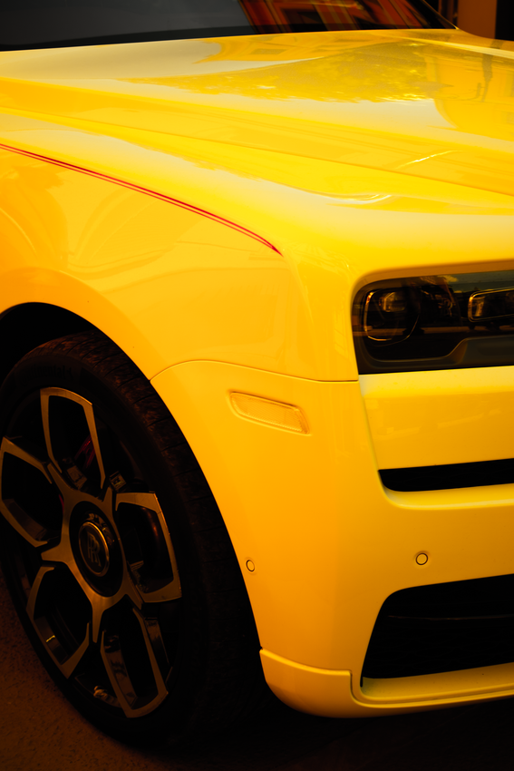 Close-up of a bright yellow sports car’s front side and wheel