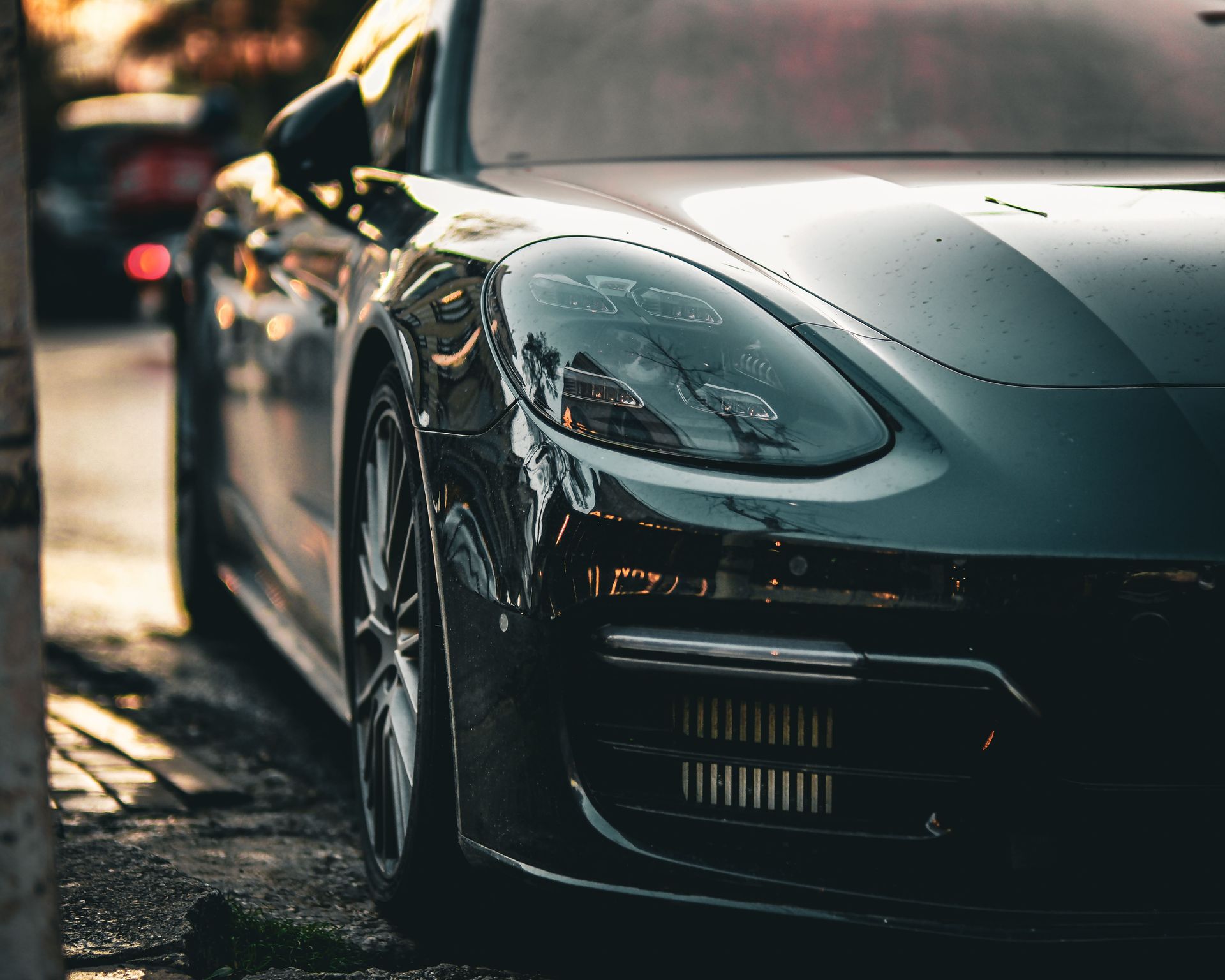 Close-up of a sleek black sports car parked on a wet street at dusk
