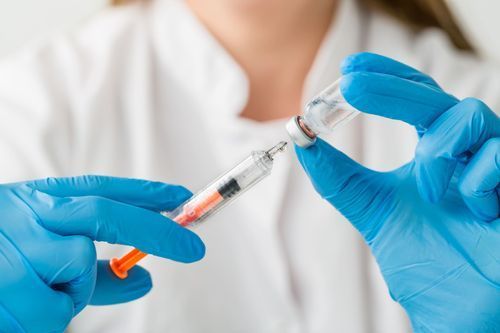 A bottle of covid-19 vaccine and a syringe on a table.