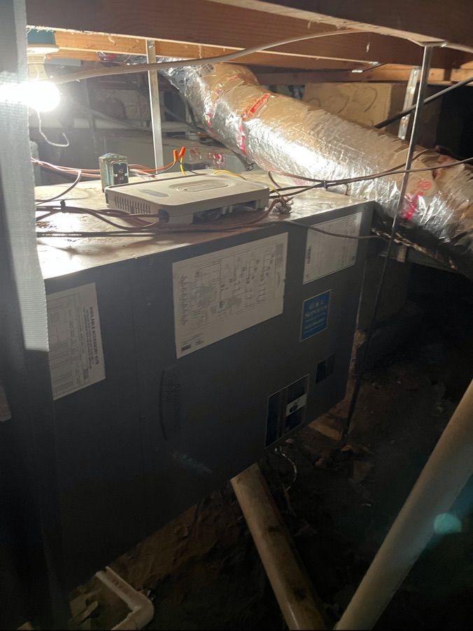 Basement HVAC unit with ductwork and exposed pipes under a low ceiling