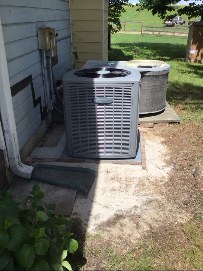 Two air conditioners are sitting on the side of a house.