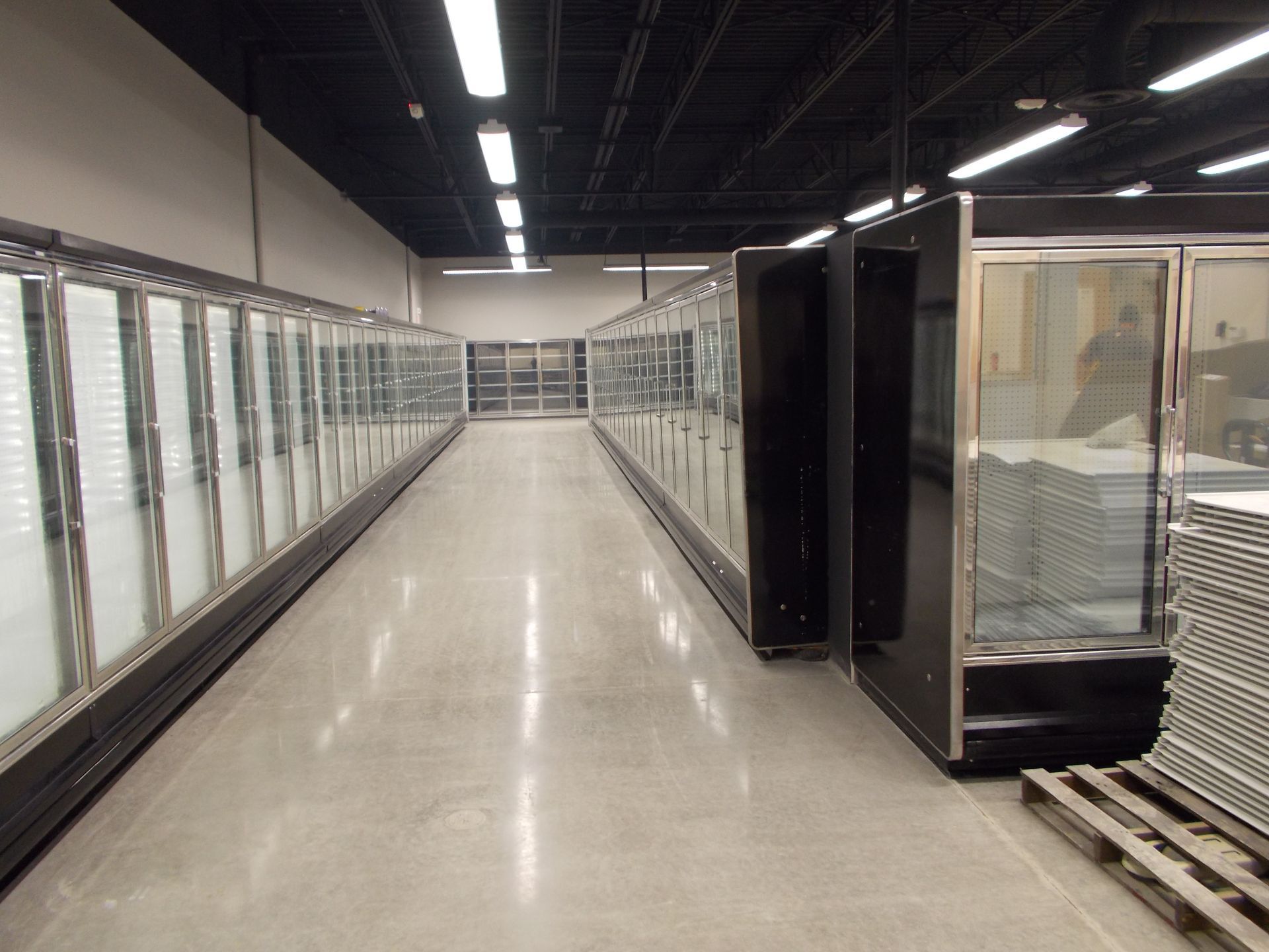 Empty supermarket aisle with glass-door freezer cases on both sides and polished floor