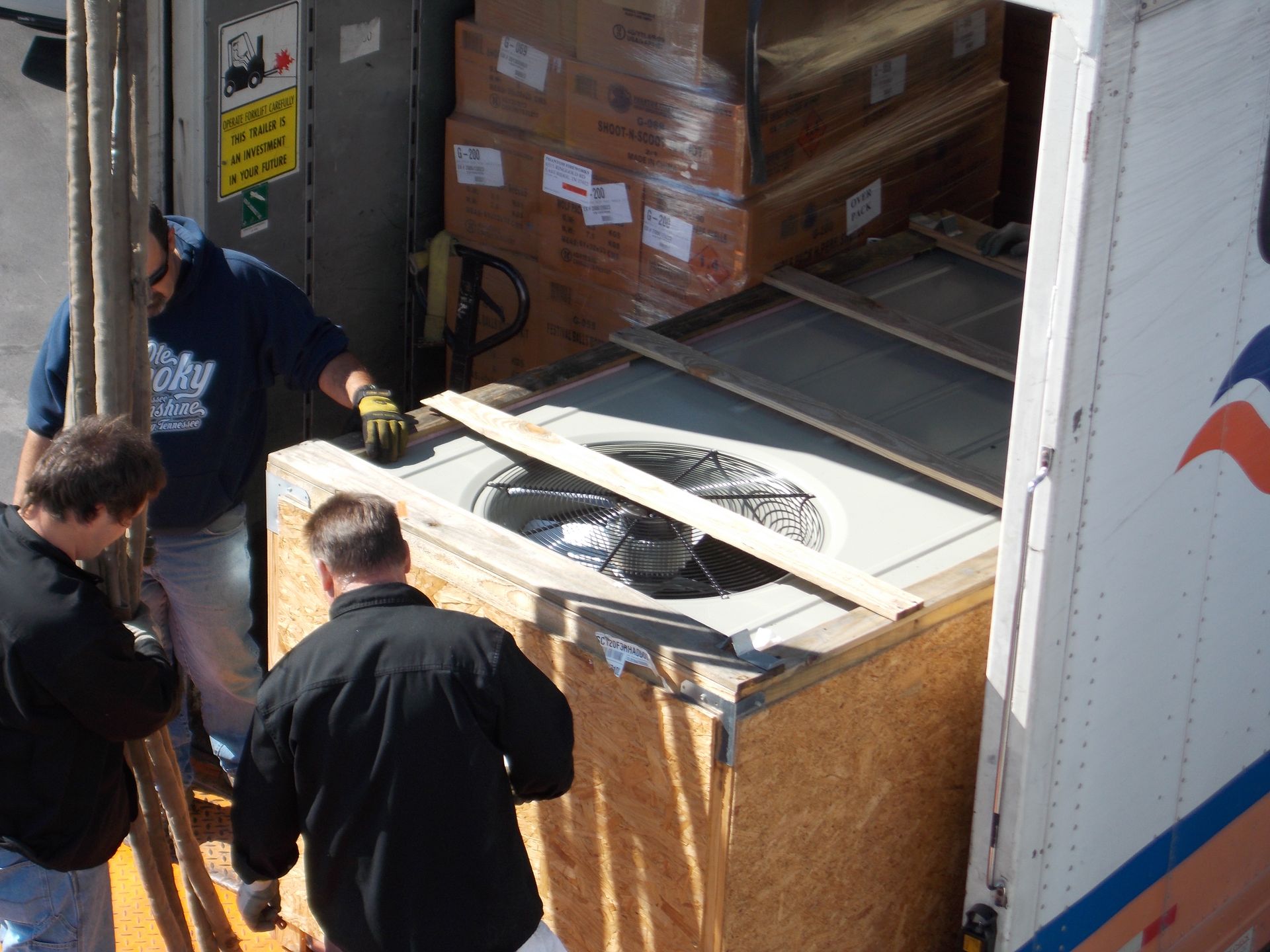 Workers loading a large crate onto a truck in a warehouse dock