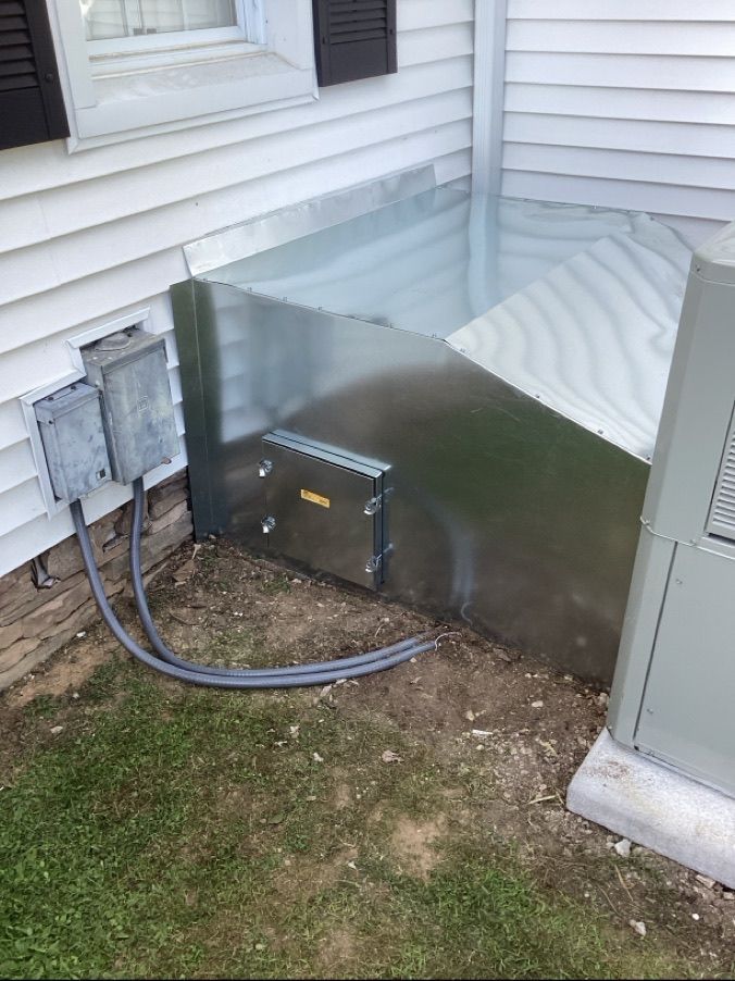 A picture of a house with an air conditioner with a hood vent on it.