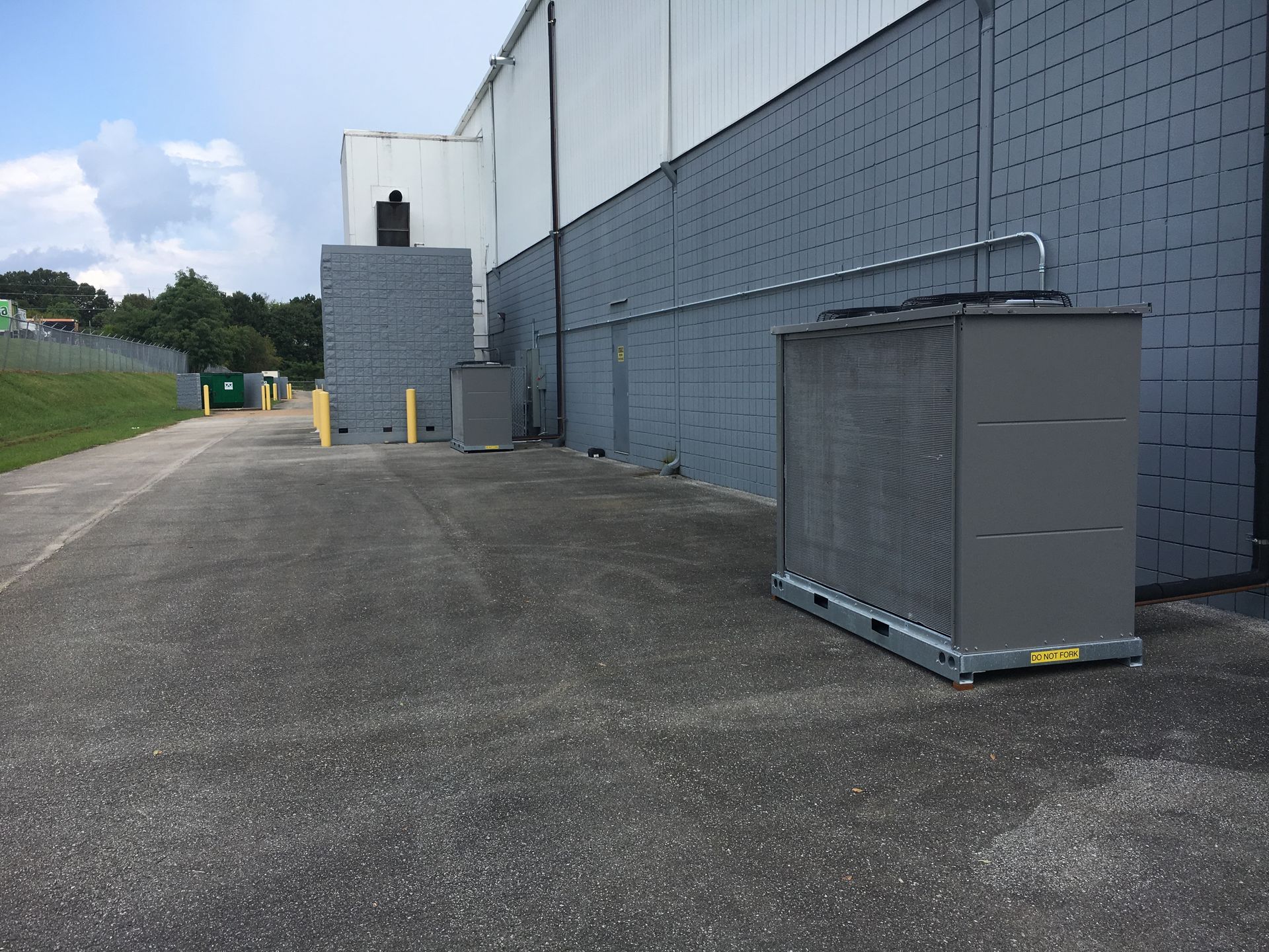Industrial building exterior with a gray storage unit on an empty paved lot