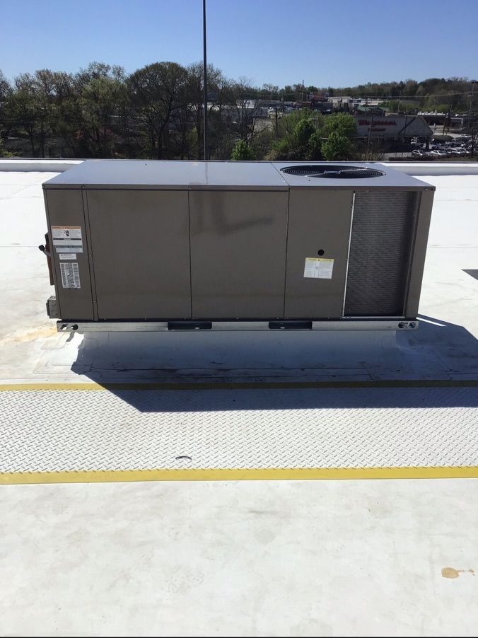 Large rooftop HVAC unit on a white rooftop with yellow safety lines under a clear sky