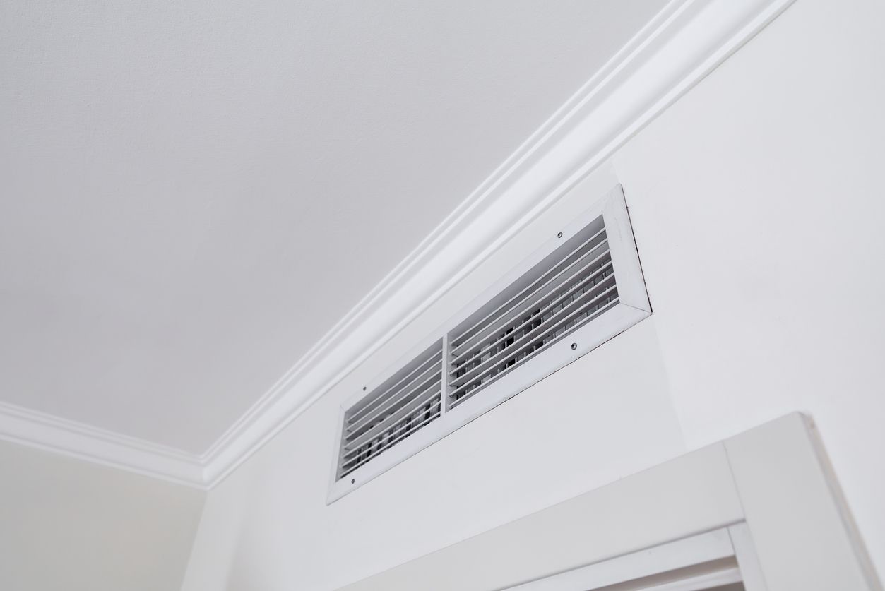 White interior wall with a ceiling air vent near crown molding above a doorway