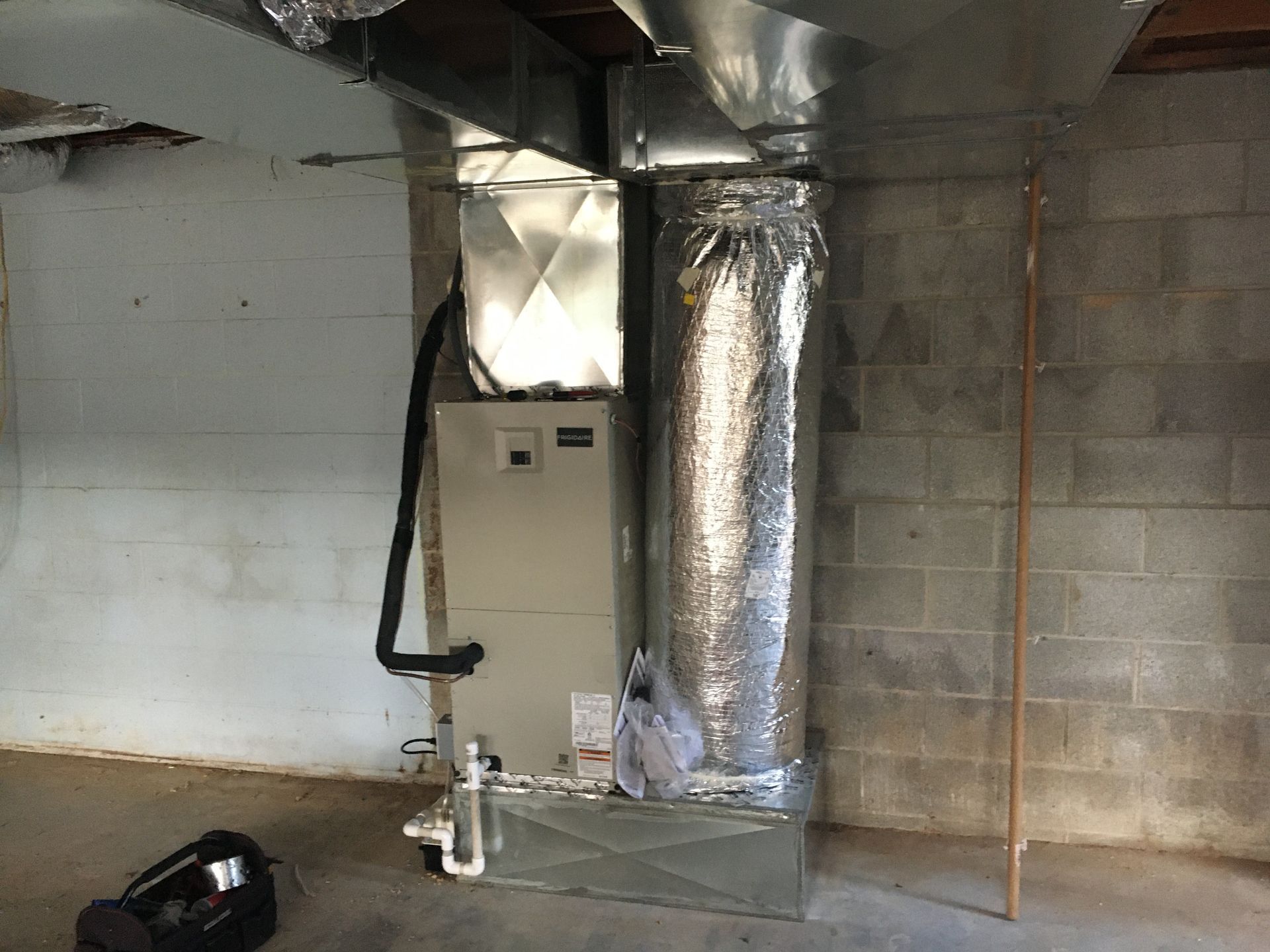 Basement utility area with furnace, ductwork, insulated HVAC duct, and concrete block walls.