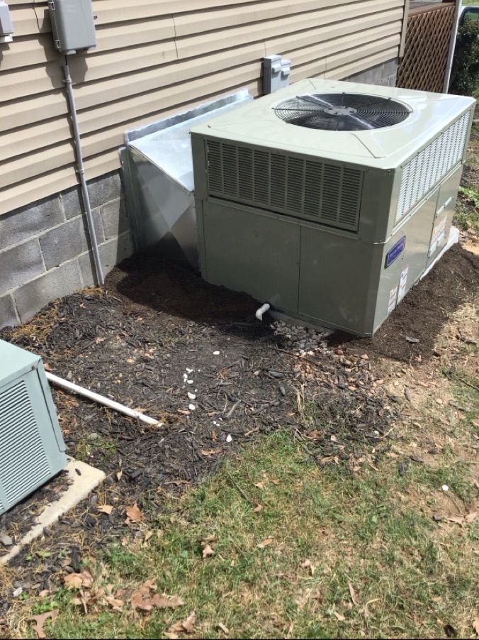 Outdoor HVAC unit beside a house, with another smaller unit partially visible in the foreground.