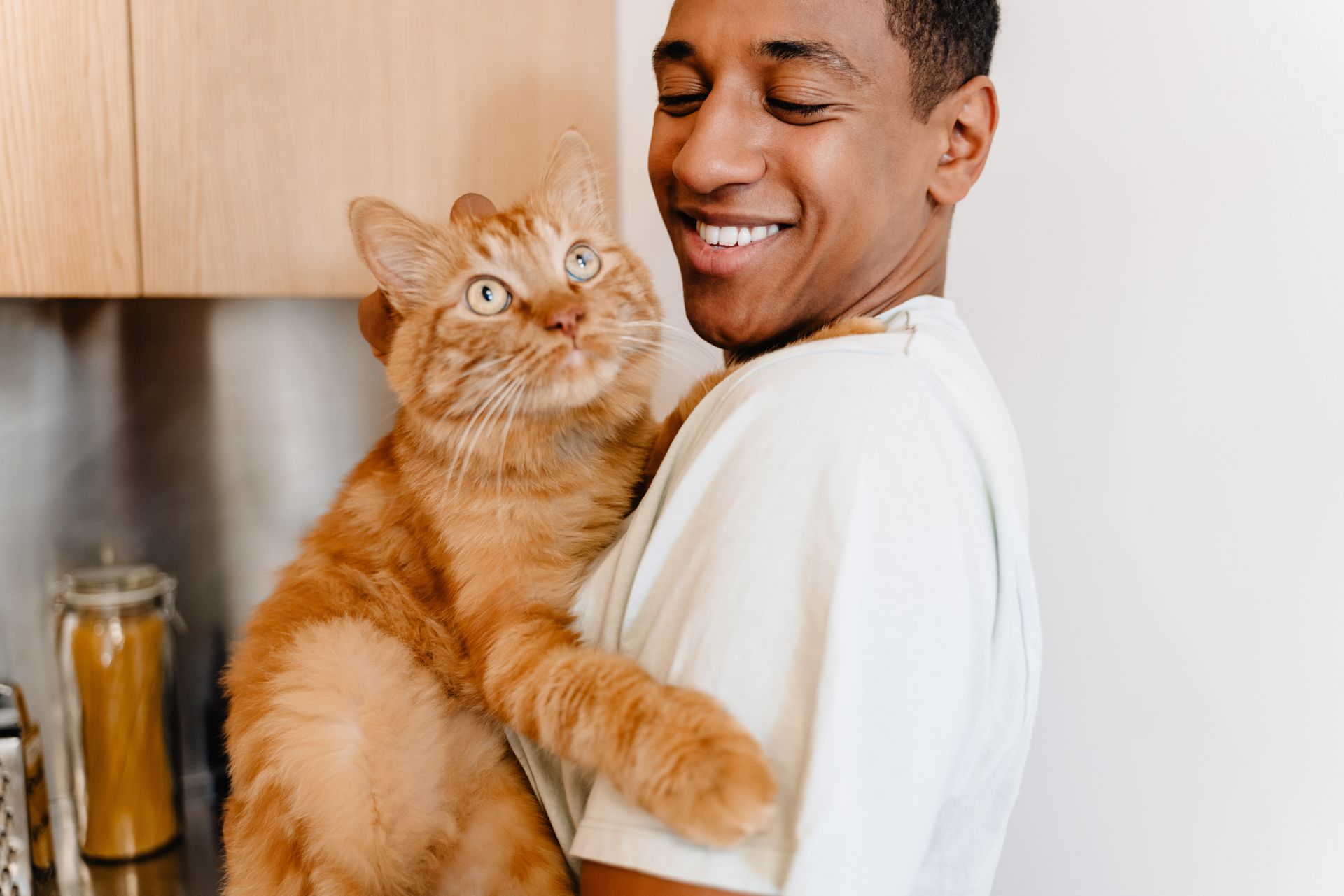 A man is holding an orange cat in his arms.