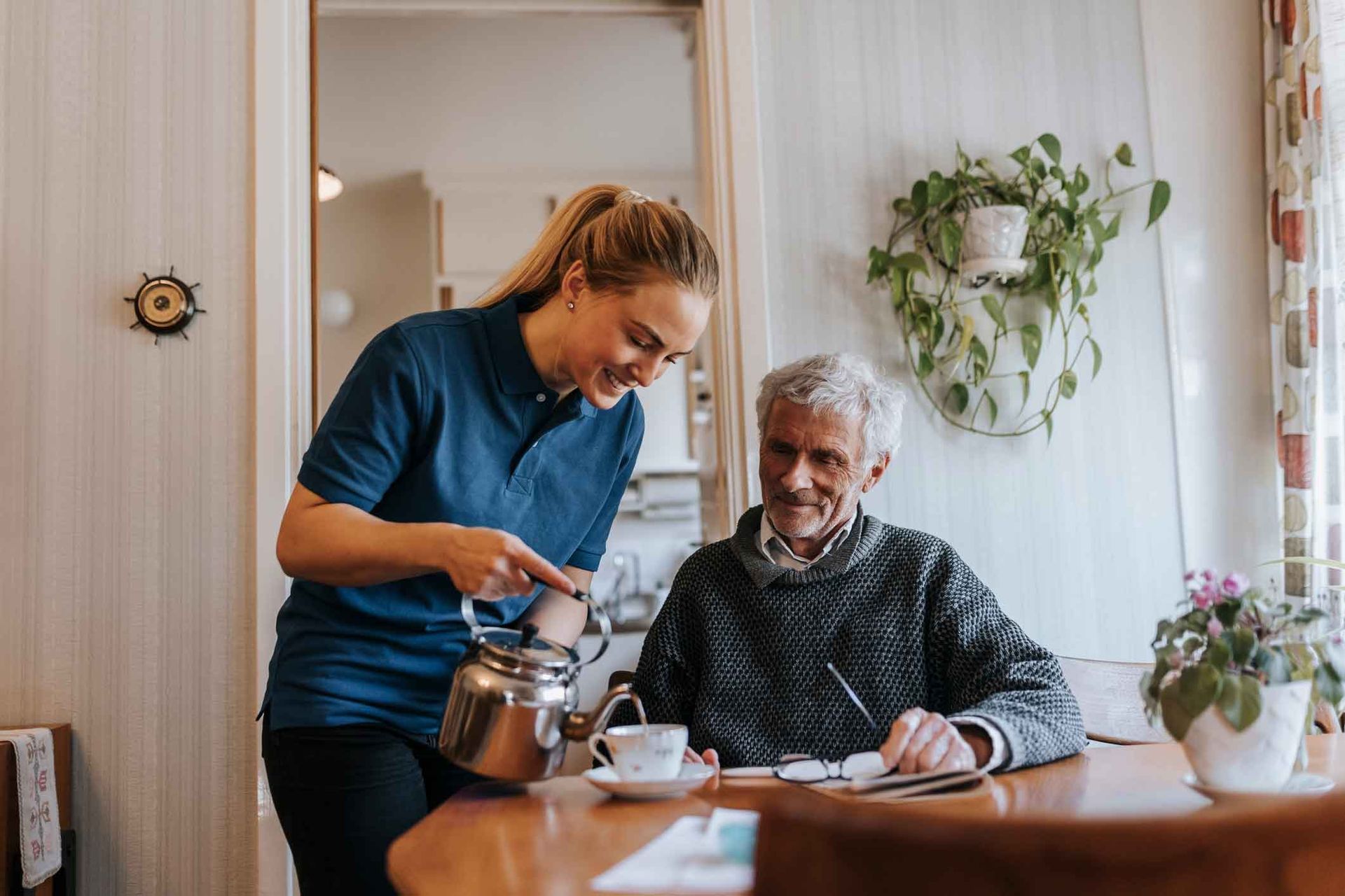 A woman is serving tea to an elderly man at a table.
