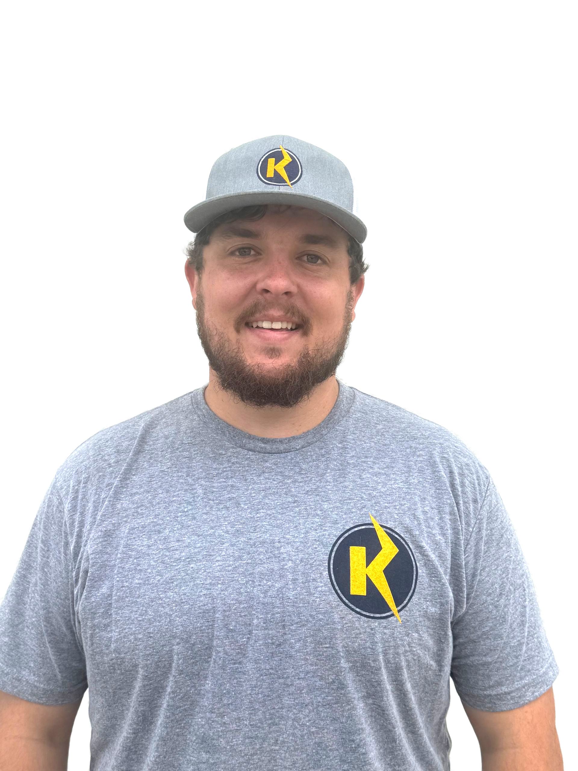 Smiling man in gray cap and T-shirt with yellow K logo on a white background