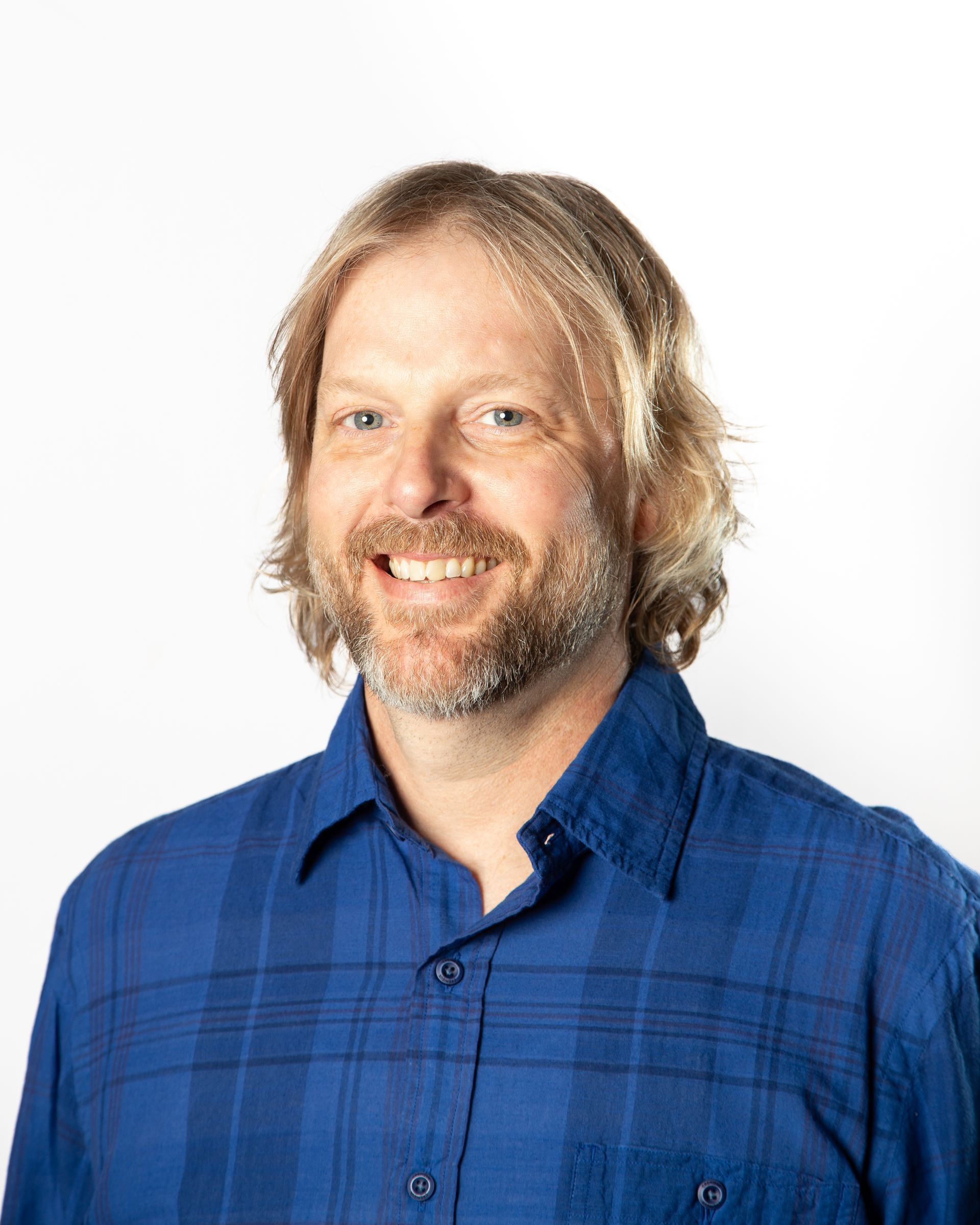 Portrait of a smiling man in a blue plaid shirt against a white background