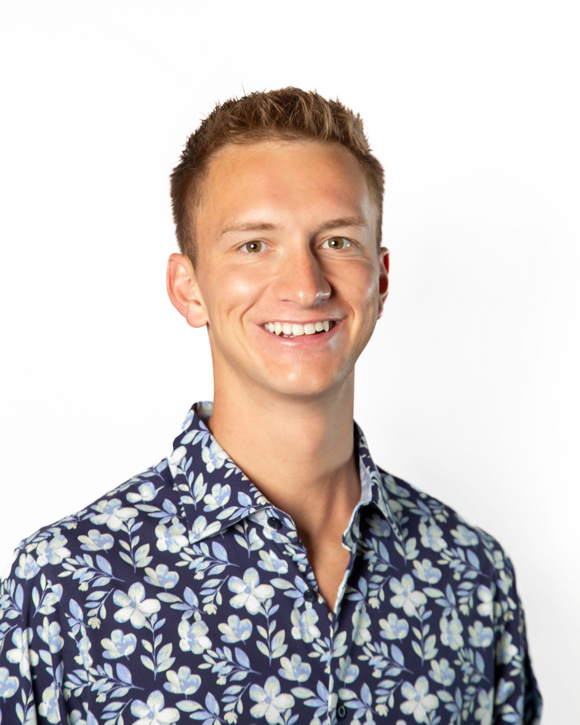Smiling person in a blue floral shirt against a white background
