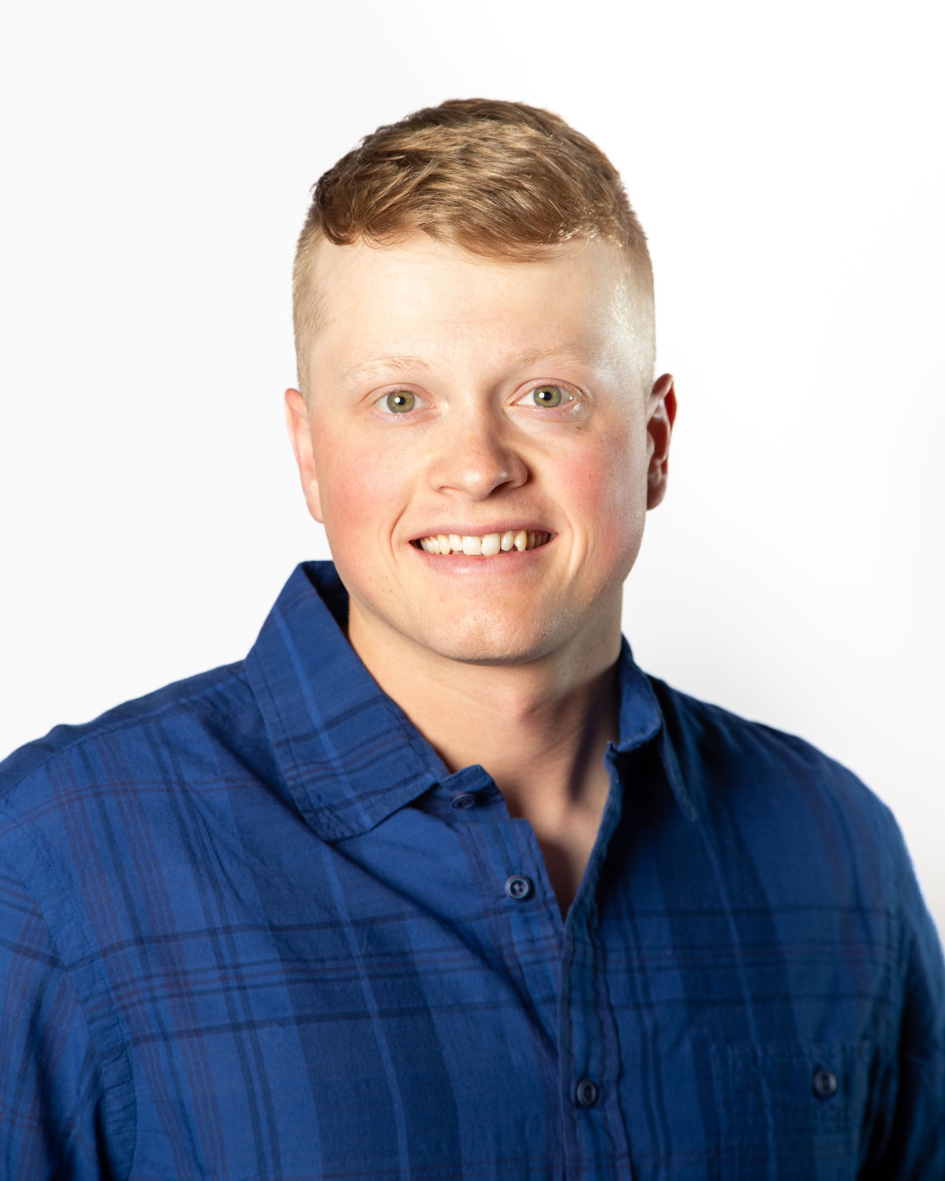 Smiling person in a blue collared shirt against a white background