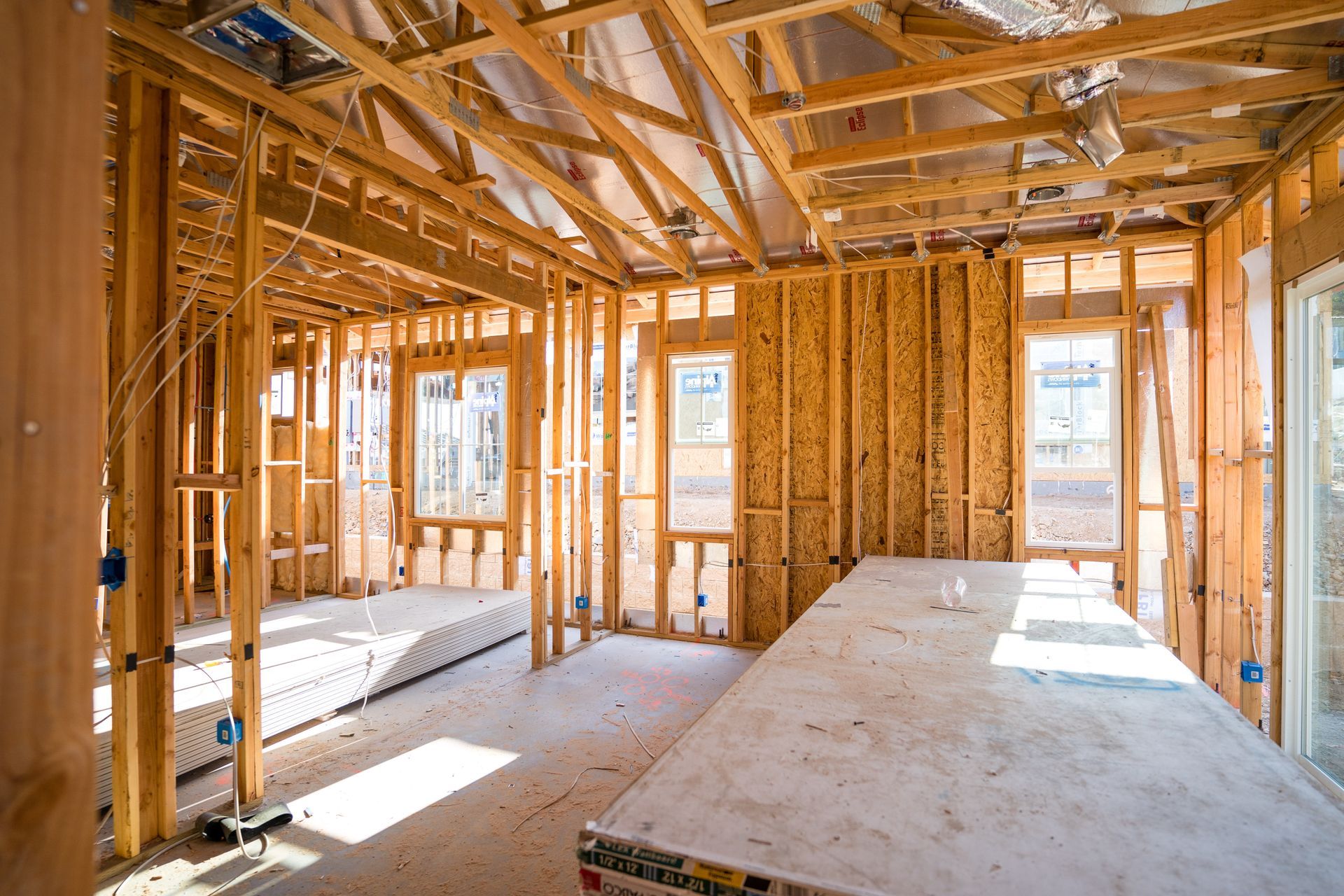 Interior of a framed house under construction with exposed wood beams and unfinished walls