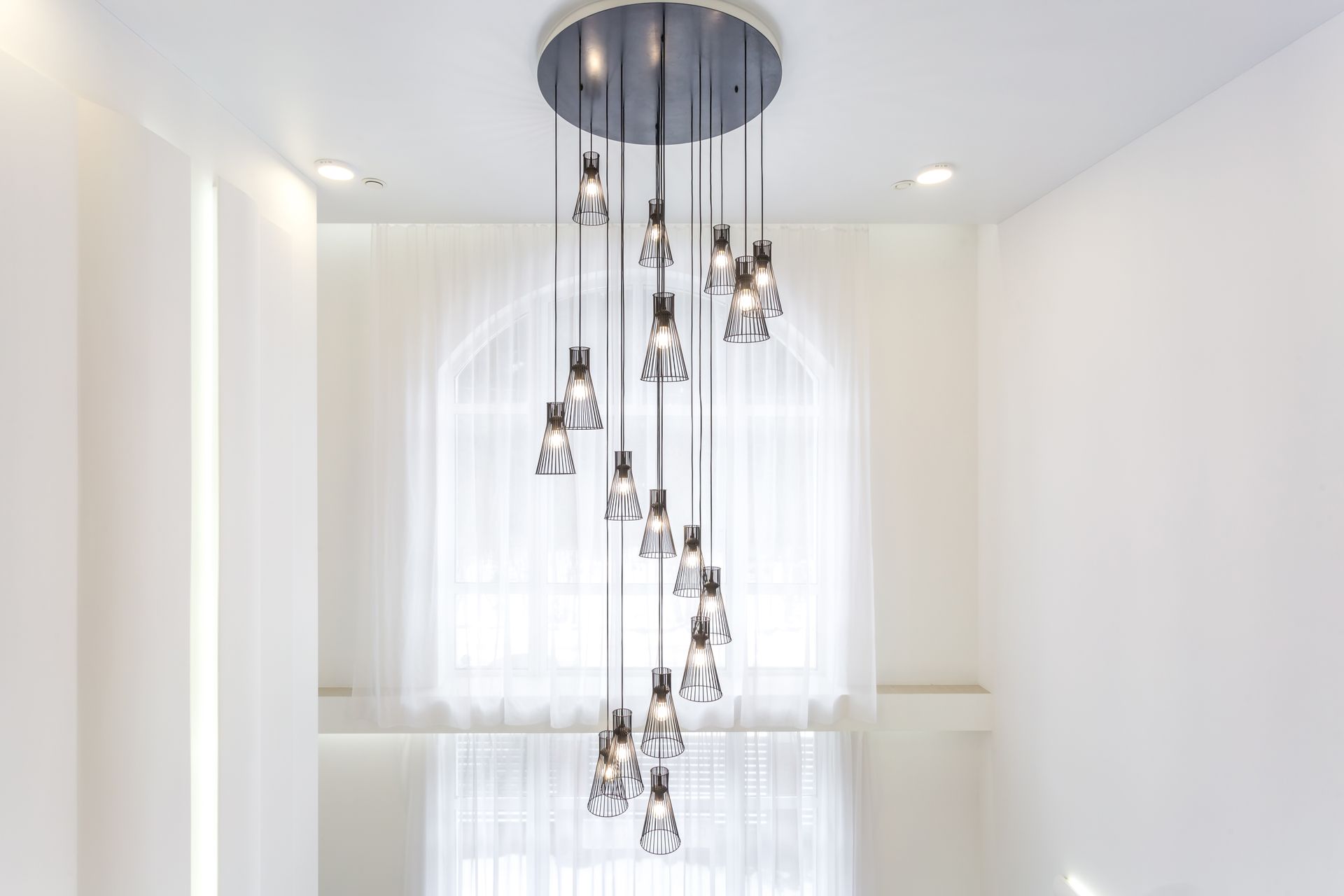 Modern chandelier with hanging glass pendants in a bright white stairwell